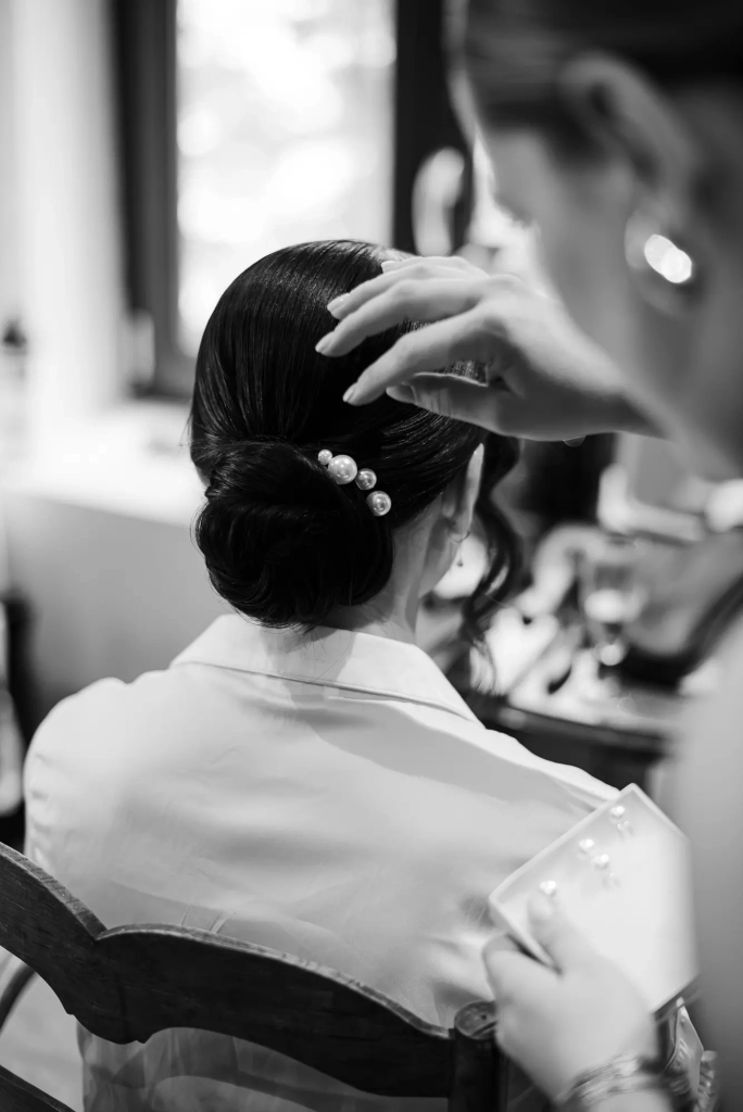 Elegant black and white photography of the bride getting her hair done for her French-American wedding near Lyon, Francee