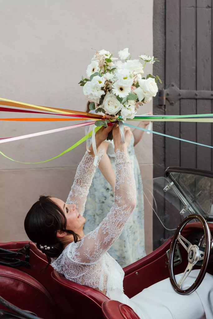 Bride holding the bouquet in the vintage car
